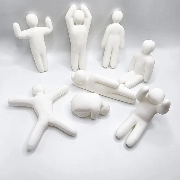 Original reference of white faceless miniature figures in standing, seated, reclining and spread-arm poses.